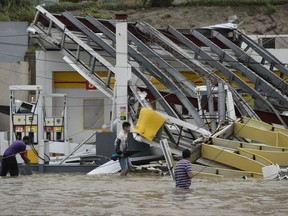 People walk next to a gas station flooded and damaged by the impact of Hurricane Maria, which hit the eastern region of the island, in Humacao, Puerto Rico, Wednesday, September 20, 2017. The strongest hurricane to hit Puerto Rico in more than 80 years destroyed hundreds of homes, knocked out power across the entire island and turned some streets into raging rivers in an onslaught that could plunge the U.S. territory deeper into financial crisis. (AP Photo/Carlos Giusti) ORG XMIT: CGPR126

PUERTO RICO OUT-NO PUBLICAR EN PUERTO RICO
Carlos Giusti, AP