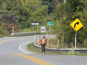 A Quebec provincial police officer searches the side of a road for clues into the disappearance of a man and a young boy in Lachute on Friday, Sept. 15, 2017. The boy was later found safe and a man, 41, was arrested.