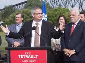 Éric Tétrault, left, candidate for a byelection in the Louis-Hebert riding, speaks at a news conference as Quebec Premier Philippe Couillard, right, looks on in Quebec City on August 15, 2017. Quebec Premier Philippe Couillard says it was clear his party's candidate in an upcoming byelection had no choice but to step down. Tétrault withdrew from the race Wednesday night after La Presse wrote about the existence of a report for his former employer on the candidate's psychological harassment of employees.