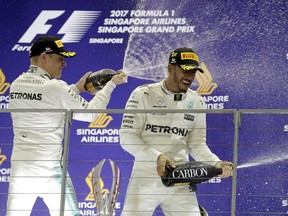 Mercedes driver Lewis Hamilton, right, of Britain is showered in champagne by teammate Valtteri Bottas of Finland as he celebrates on the podium after winning the Singapore Formula One Grand Prix on the Marina Bay City Circuit Singapore, Sunday, Sept. 17, 2017. Bottas finished in third place.