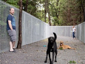 Ken Knight and Angie Jones watch as Sasha and Callie play in the access passage to the dog run in Terra-Cotta Park in Pointe-Claire on Aug. 5. The new passage allows access from Maywood Ave.