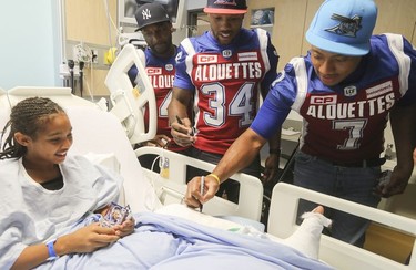 Montreal Alouettes players Darian Durant, 4, Kyries Hebert, 34, and John Bowman sign the leg cast of twelve year-old Naomi Cobbler-Roberts, during the team visit at the Montreal Children's hospital on Monday October 2, 2017.