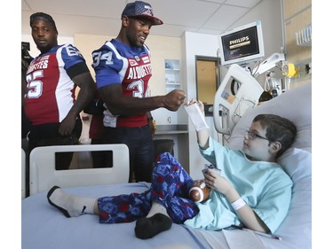 Six year-old Cole Lacharite acknowledges the Alouettes players Kyries Hebert, 34, and Jovan  Olafioye, 65, from his hospital bed at the Children's on Monday October 2, 2017.