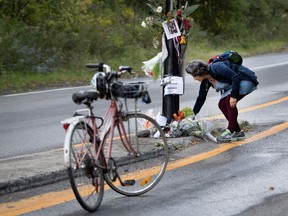A cyclist lays flowers at a memorial on Camillien-Houde Way for Clément Ouimet on Oct. 6, 2017. A coroner has concluded Ouimet's death was an accident.