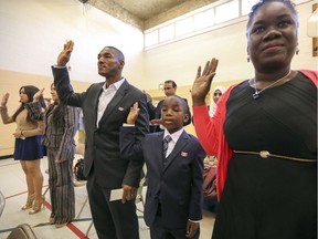 Robert Plancher and wife Darleen Hyppolite flank their son Olivier Robert as they recite the oath during ceremony giving citizenship to 40 new Canadians at the Place Cartier Adult Education Centre Allancroft Campus in Beaconsfield last Thursday. The family is originally from Haiti.