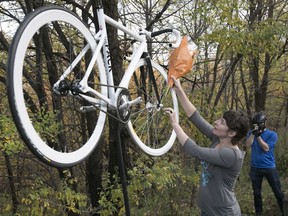 Flowers are put on the bike of Clément Ouimet during the the ghost bike ceremony on Camillien-Houde Way in Montreal, Oct. 25, 2017.