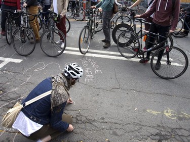A woman chalks in the name of a cyclist, "Jeanne," who died at the intersection where cycling advocates held a "die-in", at the intersection of Parc Aves and St-Viateur St. in Montreal, Oct. 28, 2017.   (Christinne Muschi / MONTREAL GAZETTE)
