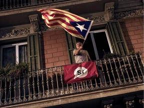 A man waves an 'Estelada' (Pro-independence Catalan flag) from a balcony after the closing of the 'Espai Jove La Fontana' (La Fontana youth center) polling station Oct. 1, 2017, in Barcelona. Spanish riot police stormed voting stations as they moved to stop Catalonia's independence referendum after it was banned by the central government in Madrid.