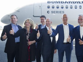 Bombardier CEO and president Alain Bellemare, centre, poses with Airbus chief executive Tom Enders, third right, and Quebec Premier Philippe Couillard, second right, along with other dignitaries and executives next to a Bombardier C Series jet during a visit to Bombardier's plant in Mirabel on Friday, Oct. 20, 2017.