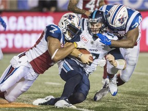 Argonauts quarterback Cody Fajardo is swarmed by Alouettes' John Bowman, left and Kyries Hebert during game in August.