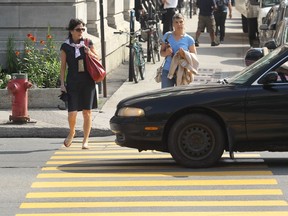 Chantal Brouillet looks towards a  driver passing his car through a cross walk on Peel St. near the intersection at Cypress St. in Montreal Wednesday, June 26, 2013 after she'd begun to cross.