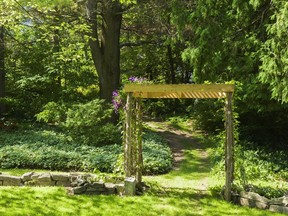 Purple clematis covers an arbor leading to a path in the Moore Garden in Mascouche. (Perry Mastrovito, special to the Montreal Gazette)