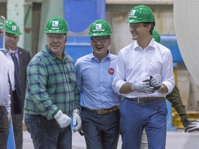 Prime Minister Justin Trudeau, right, visits the Resolute Forest Products plant with Richard Hebert, Liberal candidate for the upcoming byelection in Lac-Saint-Jean riding, centre, in Alma, Que., on Friday, October 20, 2017.