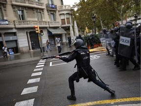 A Spanish riot police officer shoots rubber bullets straight at people trying to reach a voting site at a school assigned to be a polling station by the Catalan government in Barcelona, Spain, on Sunday, October 1, 2017.