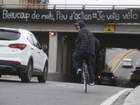 A cyclist on St-Denis St. is about to ride under a banner that appears to denounce bike-safety policies in Montreal.