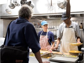 Volunteer cook Fiona Caskie gives a joking prod to fellow volunteer Kartik Shanker as they serve a meal during the NDG Food Depot opening of its new Somerled Avenue location in Montreal on Tuesday October 3, 2017.