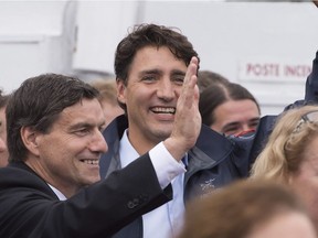 Prime Minister Justin Trudeau, centre, and local MP Denis Lemieux wave as they leave for a boat tour on the Saguenay river on Aug. 25, 2016 in Saguenay. Lemieux announced Monday he's quitting politics for family reasons.