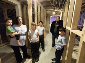 Kim Bronstein holds son, Jake Romano, 2 years old (left to right), Noah Romano, 10, Joe, 12, father Itsik Romano and Teddy, 8, as they stand in their basement, which is still being renovated after spring flooding damaged their Pierrefonds home.