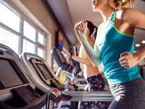 Two fit women running on treadmills in modern gym