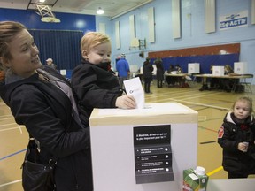 Melanie Brabant helps son Adam Cloutier cast his ballot watched by his sister Emma in Lachine. Booths for underage voters were set up at 19 polling station on Sunday.