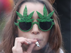 This file photo taken on April 20, 2017 shows a woman smoking marijuana on Parliament Hill waiting for the clock to hit 4:20pm on 4/20 in Ottawa, Ontario. Soon-to-be legal recreational marijuana sales in Canada could bring up to Can$1 billion (US$800 million) annually into government coffers, an official said on November 10, 2017. "If the market is somewhere in the neighborhood of 400,000 kilos (440 tons)... then the tax impact of that would be somewhere in the neighborhood of Can$1 billion," said MP and former Toronto police chief Bill Blair, who has been tasked with overseeing the setup of the new regime. / AFP PHOTO / Lars HagbergLARS HAGBERG/AFP/Getty Images LARS HAGBERG, AFP/Getty Images