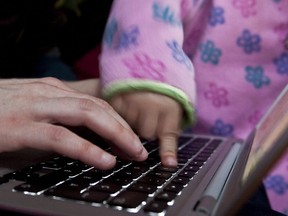 A mother and child work on laptop together.