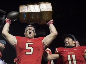 Laval Rouge et Or Vincent Alarie-Tardif, left, celebrates winning the USports Dunsmore Cup for the provincial title against the Montreal Carabins in Quebec City on Saturday, Nov. 11, 2017. Teammate Benoit Gagnon Brousseau, right, joins the celebration.