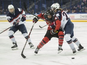 Canada's Jillian Saulnier (11), centre, fights for the puck with United States' Kacey Bellamy (22), right, during the first period of the Four Nations Cup championship hockey game in Tampa, Fla., on Nov. 12, 2017.
