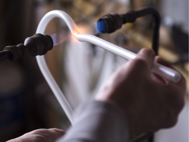 Glass artist Gerald Collard heats up glass tubing to bend it into shape in the fabrication of a neon sign.