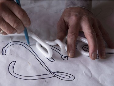 Glass artist Gerald Collard matches the lettering of a neon sign with its template.