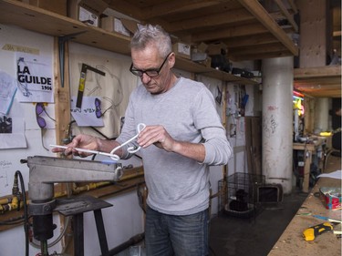 Glass artist Gerald Collard heats up glass tubing to bend it into shape in the fabrication of a neon sign.
