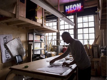 Glass artist Gerald Collard checks the lettering in the fabrication of a neon sign.