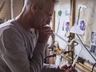 Glass artist Gerald Collard blows into the heated glass tubing to avoid kinks in the fabrication of a neon sign.