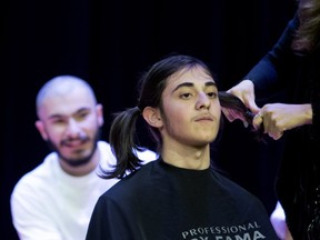 Just shaved Arthur Kayaballum watches Mgrdich Derderian have his hair pulled into pigtails as he is prepared for shaving as part of Shave to Save at Sourp Hagop Armenian school in Montreal on Wednesday.