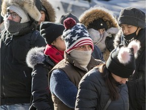 Tourists fight the cold while waiting in line to enter Notre-Dame Basilica in Montreal Sunday, Dec. 31, 2017.