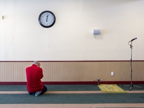A man is overcome with grief while praying at the Centre Culturel Islamique de Québec in Quebec City, Feb. 1, 2017, after some people were allowed inside for the first time since a mass shooting at the centre Jan. 29, in which 6 people were killed.