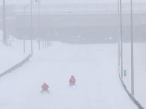 SQ officers on snowmobile, and safety crews try to clear up Highway 13 near Cote de Liesse road March 15, 2017 following massive snowstorm that left many motorists stranded overnight.