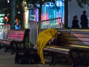 A homeless person sleeps on a park bench in Montreal in October. After the city's first cold snap in December, measures were announced to help keep the homeless safe.