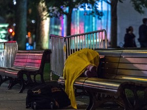 A homeless person sleeps on a park bench outside of the tent area where several Montreal business leaders spent the night in sleeping bags in a shelter set up in Dorchester Square on Thursday, October 5, 2017. Restaurant Amir Place Versailles owner Raji Abi Rached is encouraging mayor Valérie Plante to direct homeless Montrealers his way for a free meal.