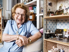 Dr. Ruth Westheimer smiles through the window of one of the dollhouses she has collected over the past 20 years. Her passion for them arises from her childhood in Nazi Germany.