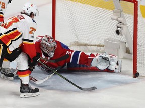 Montreal Canadiens goalie Carey Price and Calgary Flames' Sean Monahan (23) watch puck bounce of goal post, during first period NHL action in Montreal on Thursday December 7, 2017.
