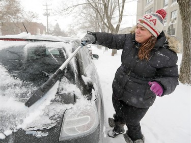 Marie-Claude Leblanc clears the snow off her car during snowstorm in Lachine Dec. 12, 2017.