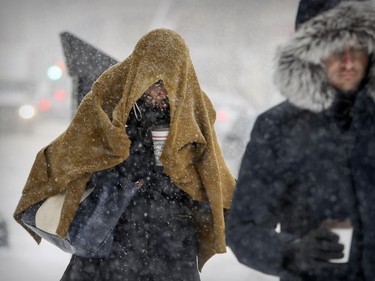 A woman drapes a cardigan over her head as she walks down Peel St. during a snowstorm in Montreal Dec. 12, 2017.