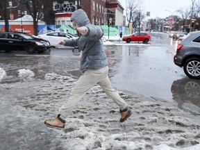 Henry Zavriyev hops over a slushy puddle at the corner of Atwater Ave. and René-Lévesque Blvd. in Montreal on Tuesday.