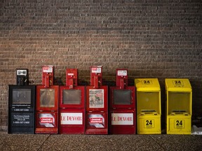 Mostly empty newspaper vending machines including boxes for The Globe and Mail, Journal de Montreal, Le Devoir, and 24 Heures outside the Universite de Montreal in Montreal on Monday, March 7, 2016