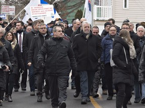 Quebec Premier Philippe Couillard, centre, and Lévis Mayor Gille Lehouillier, right, walk with hundreds of people in a march of solidarity for the Davie shipyard, in Lévis, Sunday, Dec. 3, 2017.