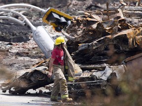 A firefighter walks by rubble on the train crash site in Lac-Megantic, Que., Sunday, July 14, 2013. The three men charged in the Lac-Megantic rail disaster that killed 47 people will not be testifying at their trial.