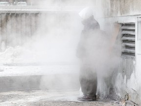 A Montrealer attempts to get warm from an exhaust at the Old Brewery Mission during a winter cold snap in Montreal