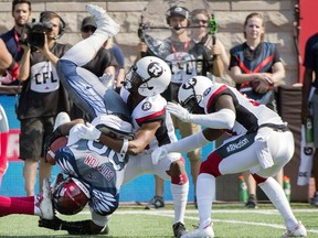 Montreal Alouettes' Tyrell Sutton is upended by Ottawa Redblacks defenders during first half against the Ottawa Redblacks in Montreal on Sept. 17, 2017.