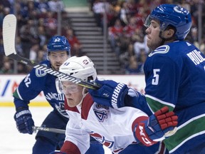 Vancouver Canucks defenceman Derrick Pouliot (5) fights for control of the puck with Montreal Canadiens left wing Daniel Carr (43) during first period NHL action in Vancouver, Tuesday, Dec. 19, 2017.